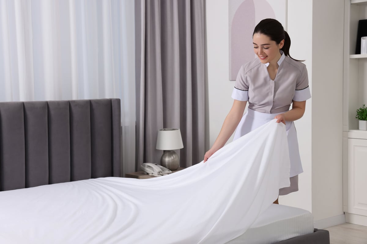 Professional cleaner making bed with fresh linens in a vacation rental — five-star ready every turnover