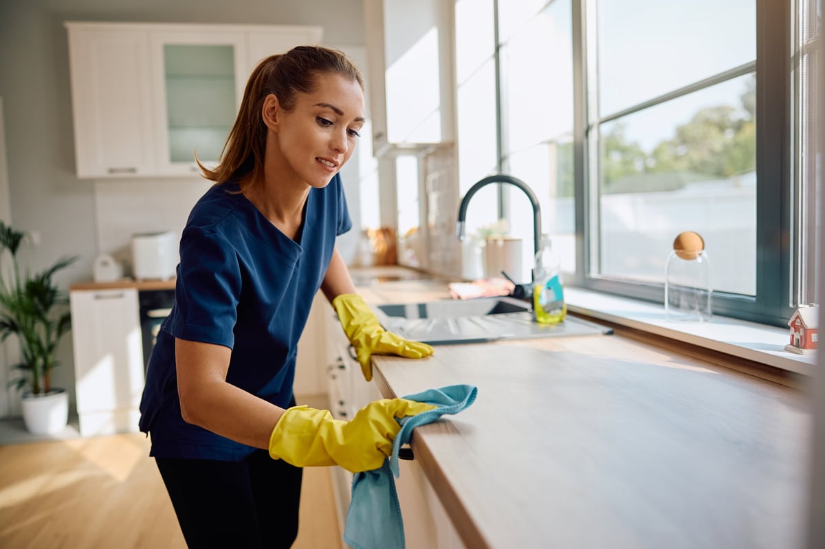 Professional housekeeper cleaning a kitchen counter — consistent standard cleaning for everyday freshness