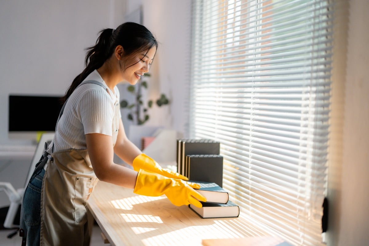 Professional cleaner wiping a wooden table with yellow gloves — consistent recurring maintenance